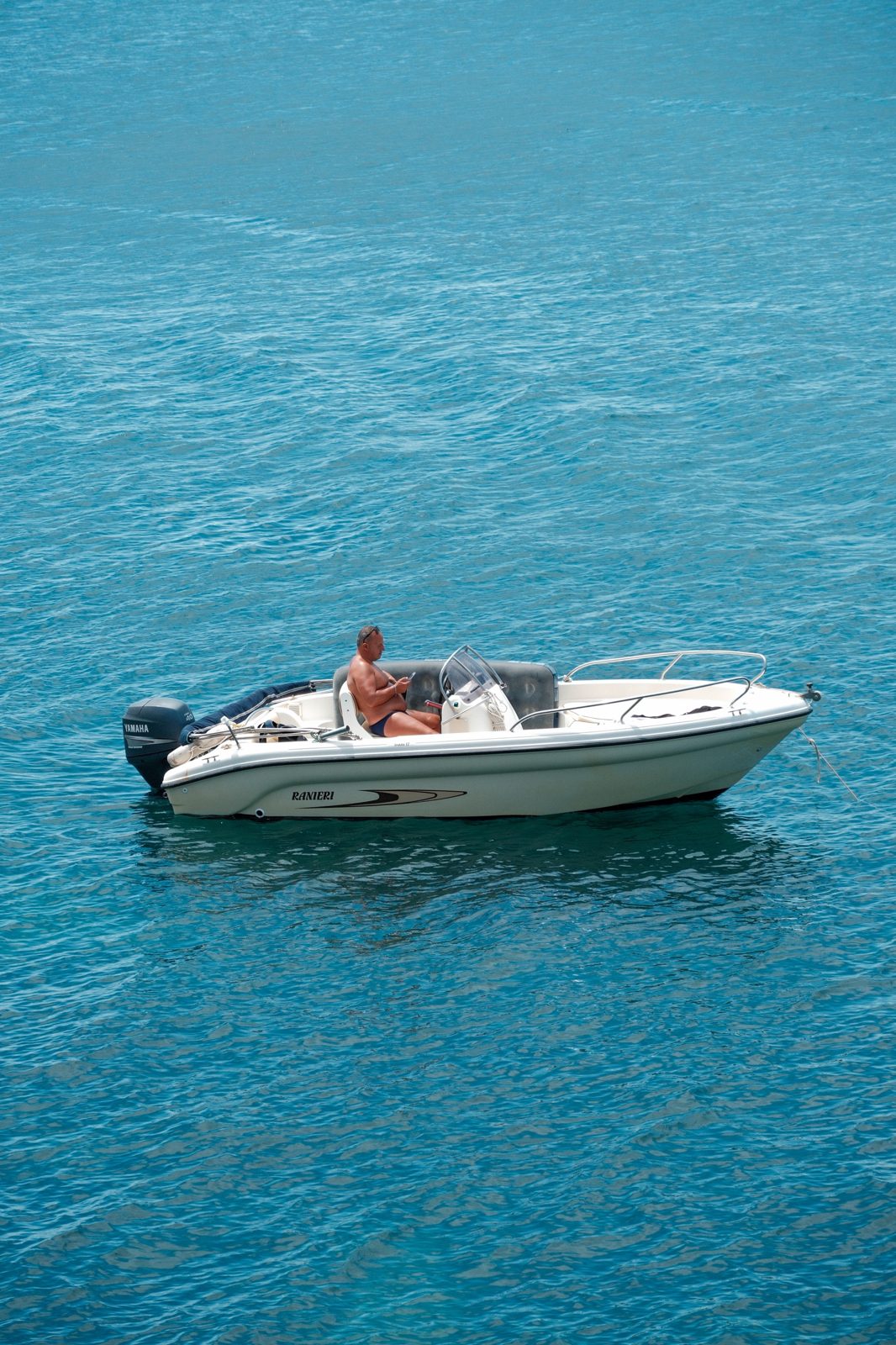 Lone boat on turquoise water off the coast of Sicily